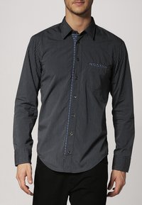 Gestreept overhemd in donkergrijs met een button-down kraag, voorzien van een contrasterende blauwe binnenkant van het knopenstrookje en een detail op de zak. Lange mouwen, slim fit.