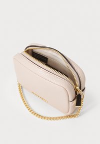 Quilted, soft pink leather crossbody bag with gold chain strap, zip closure, and beige interior lining. Features a branding tag.