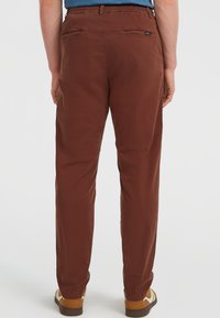 Bruine katoenen broek met een recht model, voorzien van twee achterzakken en een klein merklabel nabij de tailleband. Gestructureerde stof.