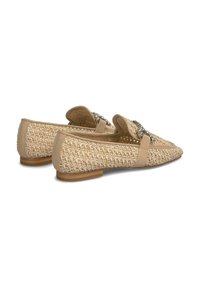 Beige woven loafers with a flat heel, featuring leather accents and a decorative buckle. The texture is smooth with a natural woven pattern.