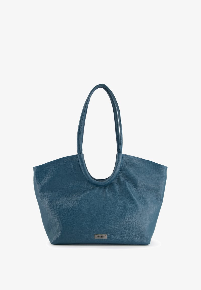 Sac tote en cuir bleu avec une texture douce, un haut arrondi et de longues poignées. Présente une petite plaque en métal avec logo sur le devant.