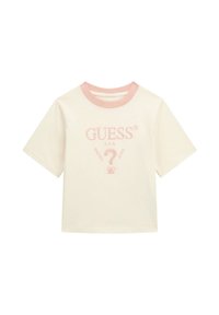 Krémové bavlněné tričko s krátkými rukávy, které má světle růžový žebrovaný límec a vyšitý logo "GUESS?" uprostřed.