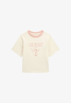 Kreemist puuvillast T-särk lühikeste varrukatega, millel on heledat roosa soonikkoes kaelus ja tikandiga "GUESS?" logo keskel.