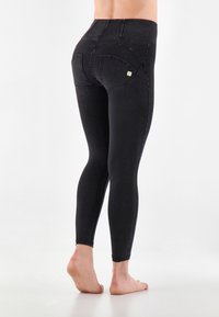 Mustat farkkuleggingsit, joissa on vartalonmyötäinen muotoilu, korkea vyötärö ja kaarevat takataskut. Sujuva pinta ja minimaaliset stitchaukset.