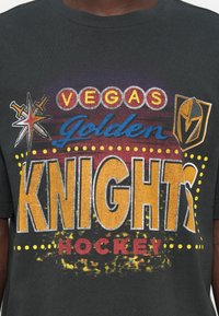 Black t-shirt featuring colorful graphic text: "VEGAS Golden KNIGHTS HOCKEY" with stars, circles, and a knight logo for team branding.