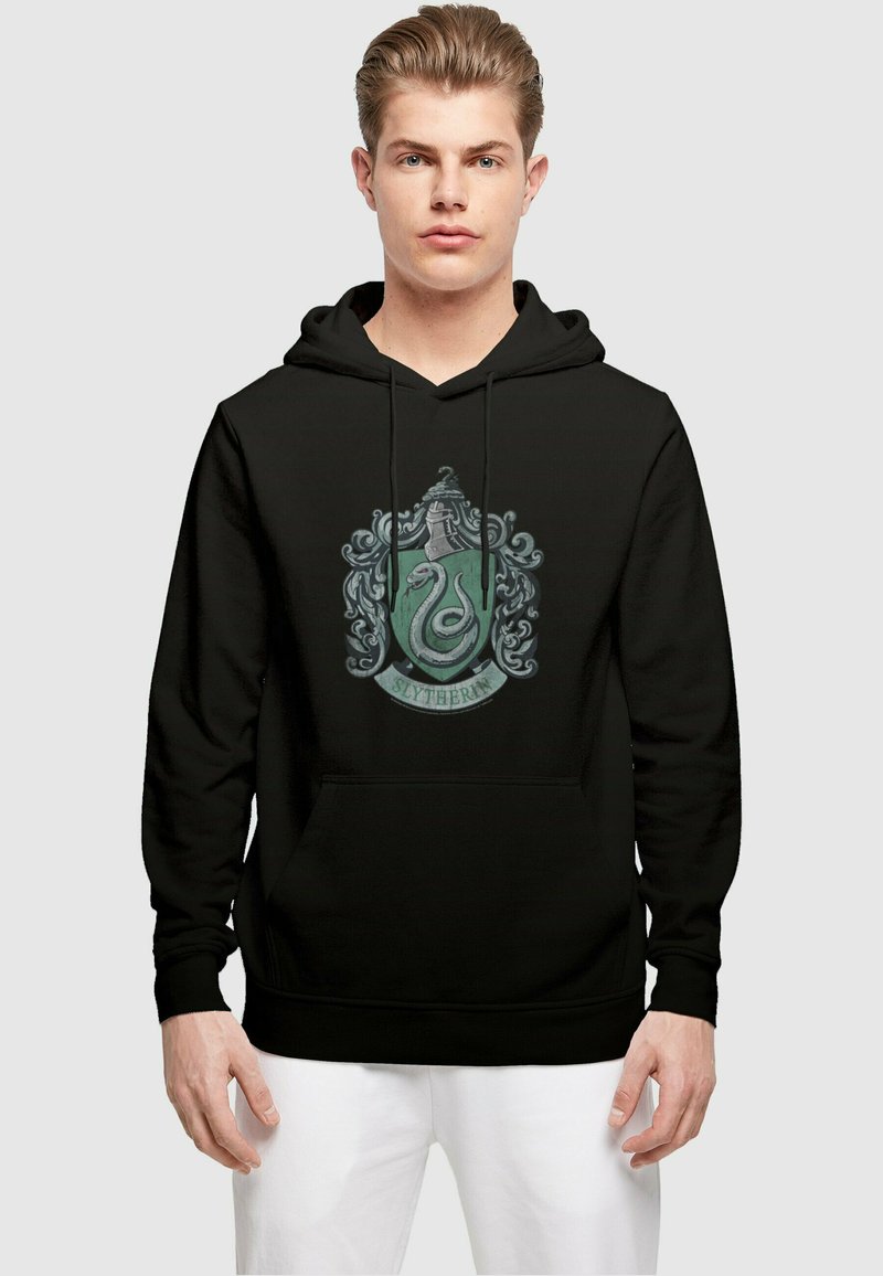 Svart hettegenser med Slytherin-våpen i grønne og sølvfargede detaljer, inkludert en detaljert slange og dekorative elementer. Kengurulomme foran.