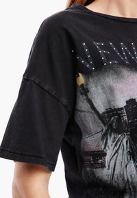 Camiseta gráfica negra de gran tamaño con la Estatua de la Libertad, con acentos de rhinestones plateados y bordes deshilachados en las mangas.