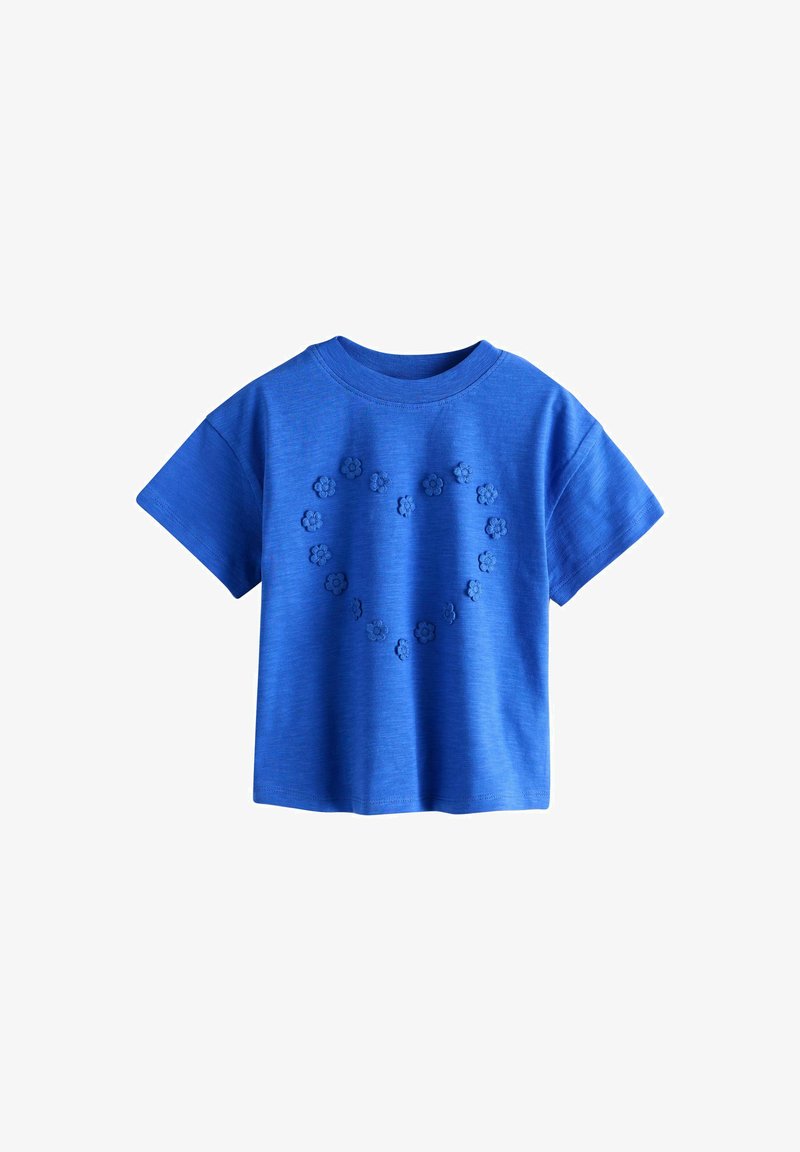 T-shirt bleu à manches courtes avec de petites fleurs en relief disposées en forme de cœur sur le devant, sur fond blanc.
