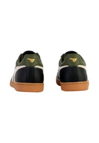 Zapatillas de cuero negro con acentos en blanco y verde oliva, que presentan una suela de goma y un sutil logo dorado en el talón.