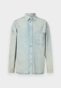 Camisa de mezclilla azul claro con cierre de botones en la parte delantera, cuello puntiagudo, mangas largas y un bolsillo en el pecho. Textura desgastada y costuras visibles.