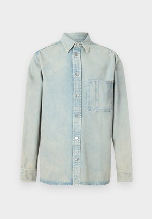 Ανοιχτό μπλε τζιν πουκάμισο με κούμπωμα μπροστά, μυτερό γιακά, μακριά μανίκια και μία τσέπη στο στήθος. Ξεθωριασμένη υφή και ορατές ραφές.