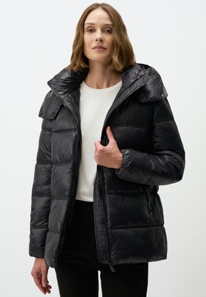 Black puffer jacket with a shiny finish, zippered front, and hood. Features a boxy shape and ribbed cuffs, worn over a white shirt.