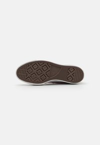 Brown rubber shoe sole with a textured, geometric pattern and a white border. Features a smooth edge and logo imprint on the tread.