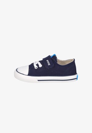 Zapato de lona navy con punta de goma blanca, cierre con cordones y correa de Velcro. Presenta un acento azul en el talón y una suela blanca con una raya navy.