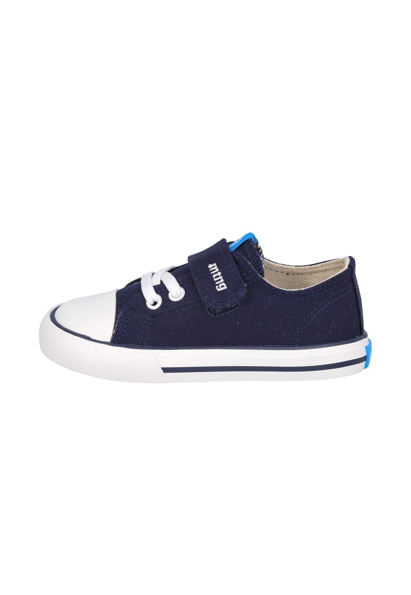 Zapato de lona navy con punta de goma blanca, cierre con cordones y correa de Velcro. Presenta un acento azul en el talón y una suela blanca con una raya navy.