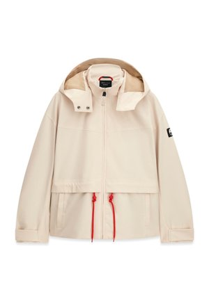 Veste beige à capuche avec fermeture éclair devant, cordons rouges réglables à la taille, poches latérales, poignets en velcro et écusson de marque sur la manche gauche.