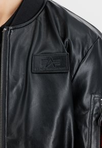 Μαύρο δερμάτινο μπόμπερ τζάκετ με κλείσιμο με φερμουάρ, ραμμένο γιακά και υφασμένο λογότυπο στη αριστερή πλευρά του στήθους. Εσοχές τσέπες στους ώμους.