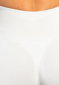 Witte ribstof met een gladde tailleband en naadloos ontwerp. De gestructureerde oppervlakte vertoont fijne lijnen en een subtiele glans.