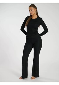 Schwarzes Langarmoberteil und passende, ausgestellte Hose aus weichem Stoff. Das Outfit zeichnet sich durch ein tailliertes Design und eine glatte Textur aus.