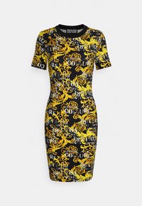 Robe moulante en tissu extensible. Fond noir orné de motifs baroques jaunes et de texte répété "VERSACE COUTURE" en blanc.