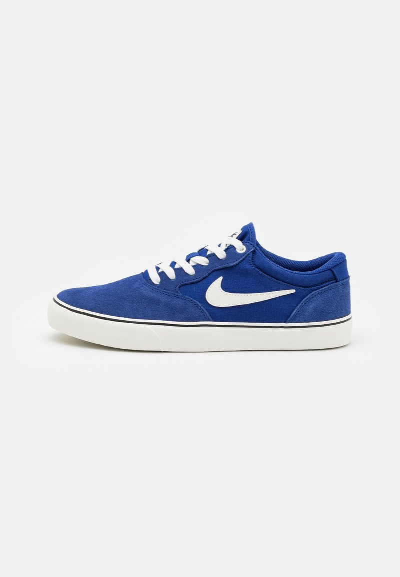 Baskets Nike bleues avec logo swoosh blanc, lacets blancs et semelle blanche avec bordure noire, vues de côté sur un fond uni.
