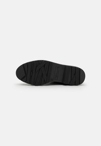 Suola di scarpa in gomma nera con un motivo a battistrada geometrico e logo del marchio, progettata per la presa e la durata.