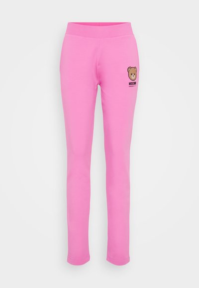 Roza bombažna legging hlače s mehko teksturo, ki vsebujejo grafiko medveda in logotip "Moschino" na levi strani, zasnovane za vsakodnevno nošenje.