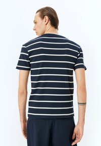 Marineblaues, geripptes T-Shirt mit kurzen Ärmeln und weißen horizontalen Streifen, mit Rundhalsausschnitt und lässiger Passform. Keine sichtbaren Marken oder Logos.