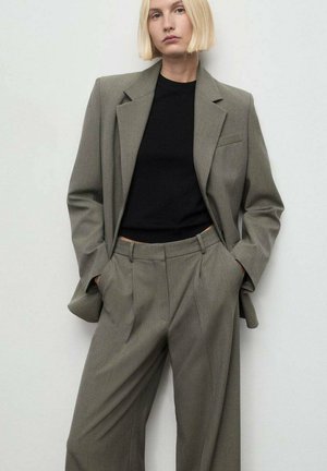 Blazer gris de gran tamaño combinado con pantalones de pierna ancha a juego, ambos con una tela texturizada. Top negro ajustado debajo.