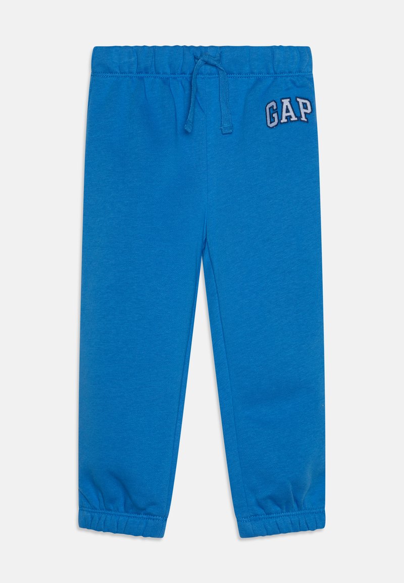 Pantalon de jogging bleu avec une ceinture élastique et un cordon de serrage. Présente des poignets froncés et un logo "GAP" brodé en haut à gauche.