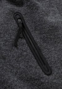Grau gefilzter Stoff mit einem sichtbaren schwarzen Reißverschluss. Der Reißverschluss ist gerade und hat einen Stoff-Zugring, der nahtlos in das Material integriert ist.