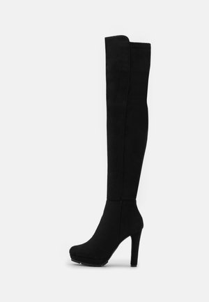 Botte noire montante à talon avec un talon plateforme haut et une tige lisse et ajustée.