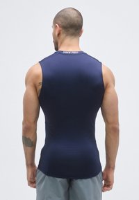 Top atletico smanicato blu navy realizzato in tessuto elasticizzato. Presenta una scollatura rotonda e un design aderente, con un'etichetta "NIKE PRO" sul retro.