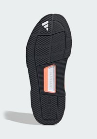 Black rubber shoe sole with a textured pattern. Features a silver and orange accent near the center labeled "REPETITOR" and "TRAXION."