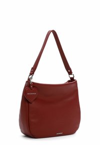 Sac à main en cuir rouge avec une texture lisse, une bandoulière et une étiquette en forme de cœur affichant le nom de la marque.