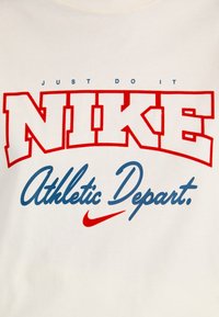 Witte T-shirt met "JUST DO IT" in het blauw, "NIKE" in vet rood, en "Athletic Depart." in cursief blauw, met een rode Nike swoosh als accent.
