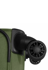 Valigia da viaggio in tessuto verde con ruote in plastica nera. Le ruote hanno un design circolare con fori di ventilazione. Dettagli di costruzione durevoli visibili.