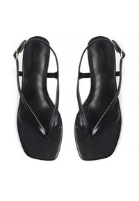 Zwarte teensandalen met platte zolen, gemaakt van soepel leder. Voorzien van slanke banden en een vierkante teenontwerp. Gespsluiting op de enkel.