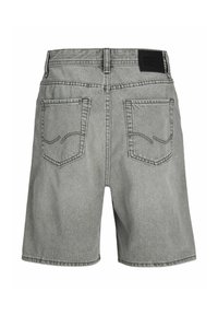 Hallid teksapüksid, millel on tagataskud ja must kaubamärgiga silt vöörihma peal, näidatud tagantpoolt.