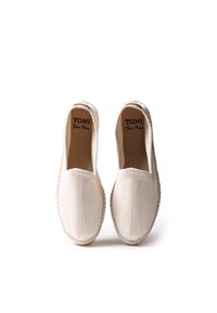 Espadrilles de lona blanca con textura de espiga, paneles elásticos laterales y suela de yute trenzado. Logotipo de la marca visible en el forro interior.