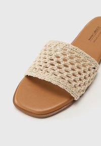 Infradito in fibra naturale con una fascia intrecciata beige e una soletta marrone liscia. Design con punta quadrata e suola piatta.