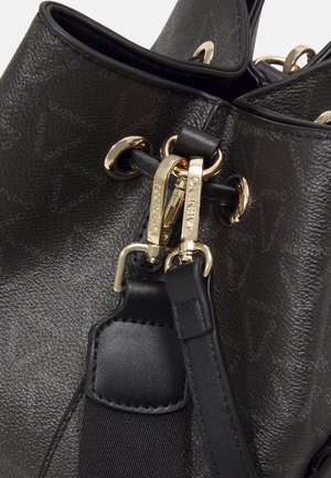Black textured leather bag with gold hardware. Features a drawstring closure, metallic accents, and a detachable strap.