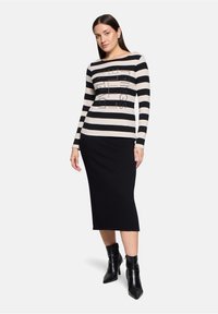 Zwart en crèmekleurig gestreept langmouwen shirt met grafisch ontwerp en zwarte pencil skirt, gedragen met zwarte enkellaarsjes. Soepele katoenmix stof.