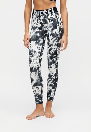 Kvinde iført sort-hvide tie-dye leggings med en bred sort linning med fed hvid "DIESEL" tekst.