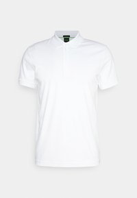 Vit polo skjorta i bomull, med klassisk krage, treknappslå och korta ärmar. Subtil logotyp på bröstet.
