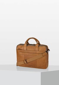 Braune Ledertasche für Laptops mit zwei Griffen, einem abnehmbaren Schultergurt und einer Vorderklappe mit Details. Glatte Textur und strukturierte Form.