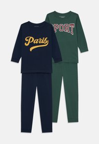 Twee sets kinderpajama's: één marineblauw met "Paris" in gele spraakletters, de andere groen met "SPORT" in witte en rode blokletters.
