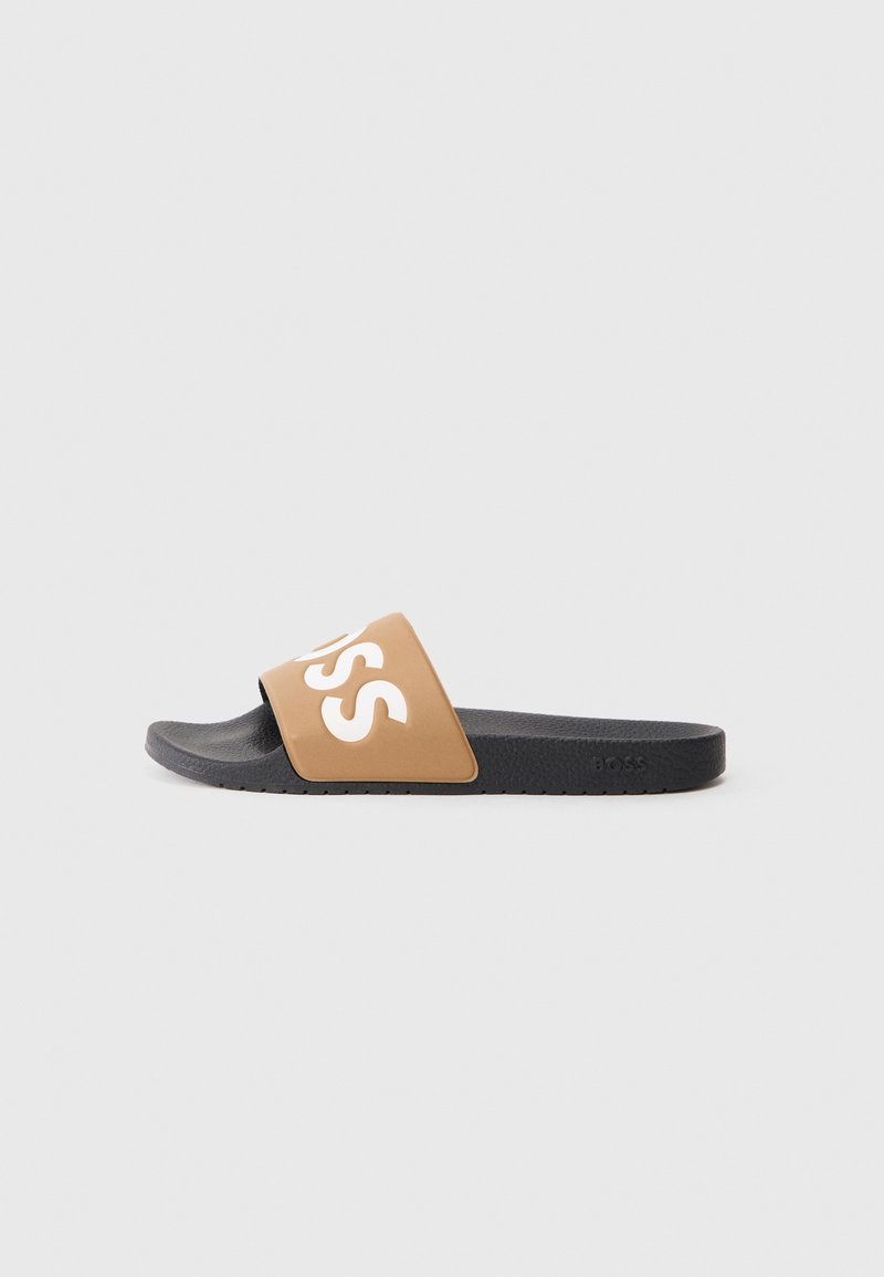 Brūna slip-on tipa sandalė ar plašu siksnu ar baltu "BOSS" logotipu; melna teksturēta zolīte nodrošina saķeri un komfortu.