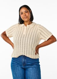 Beežist kootud lühikeste varrukatega polosärk, millel on tekstuuriga muster ja krae, kombineeritud siniste teksapükstega.