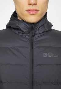 Giubbotto puffer nero con zip frontale, colletto alto e cappuccio. Caratterizzato da un motivo a rombi orizzontali e un logo discreto sul petto. Tessuto morbido.